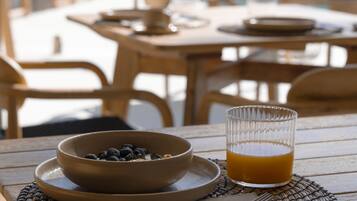 A wooden table with a bowl of blueberries, a glass of orange juice, and a cup and saucer.