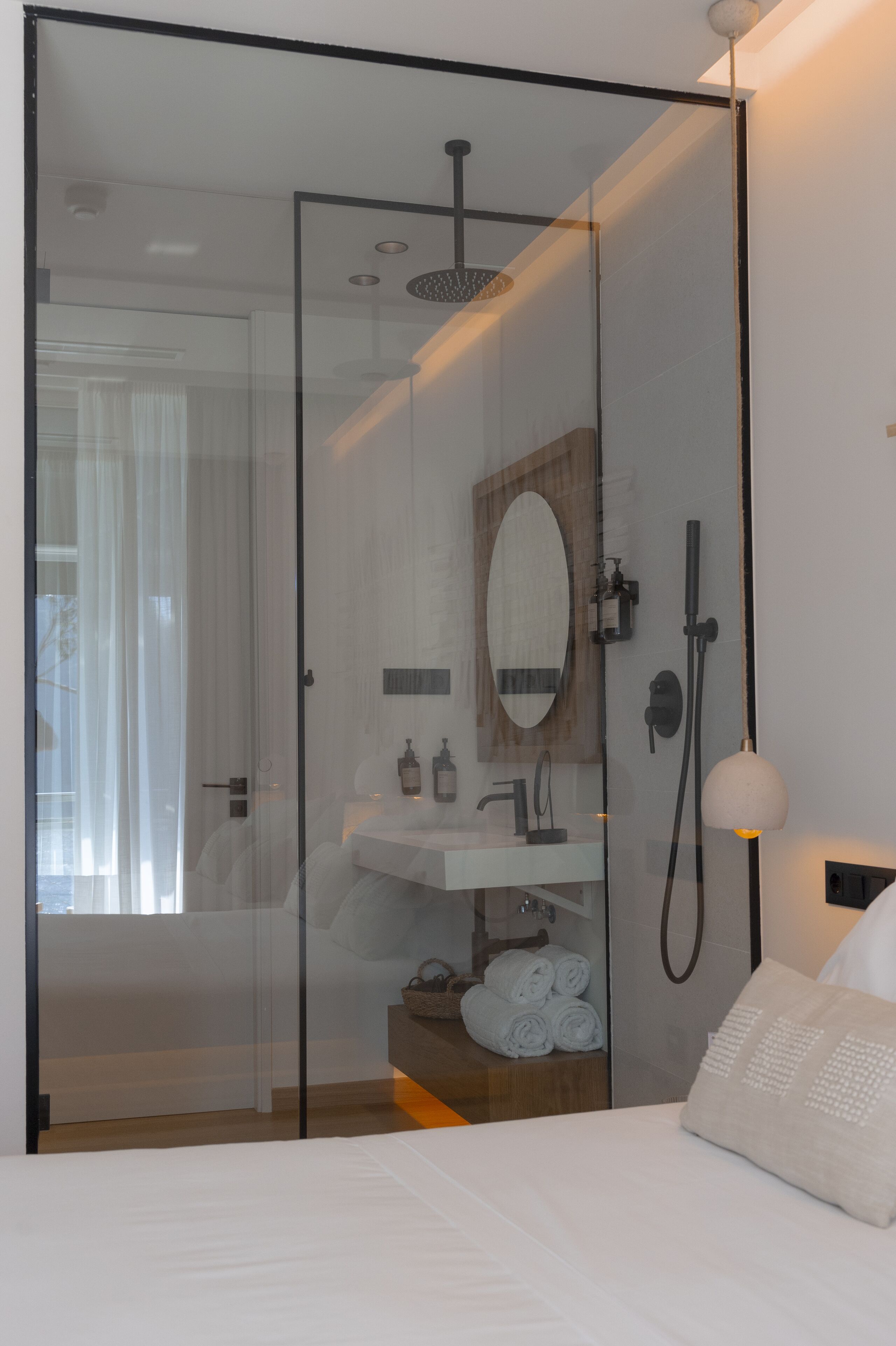 A modern bathroom with a glass shower enclosure, a wooden vanity, and a large mirror.