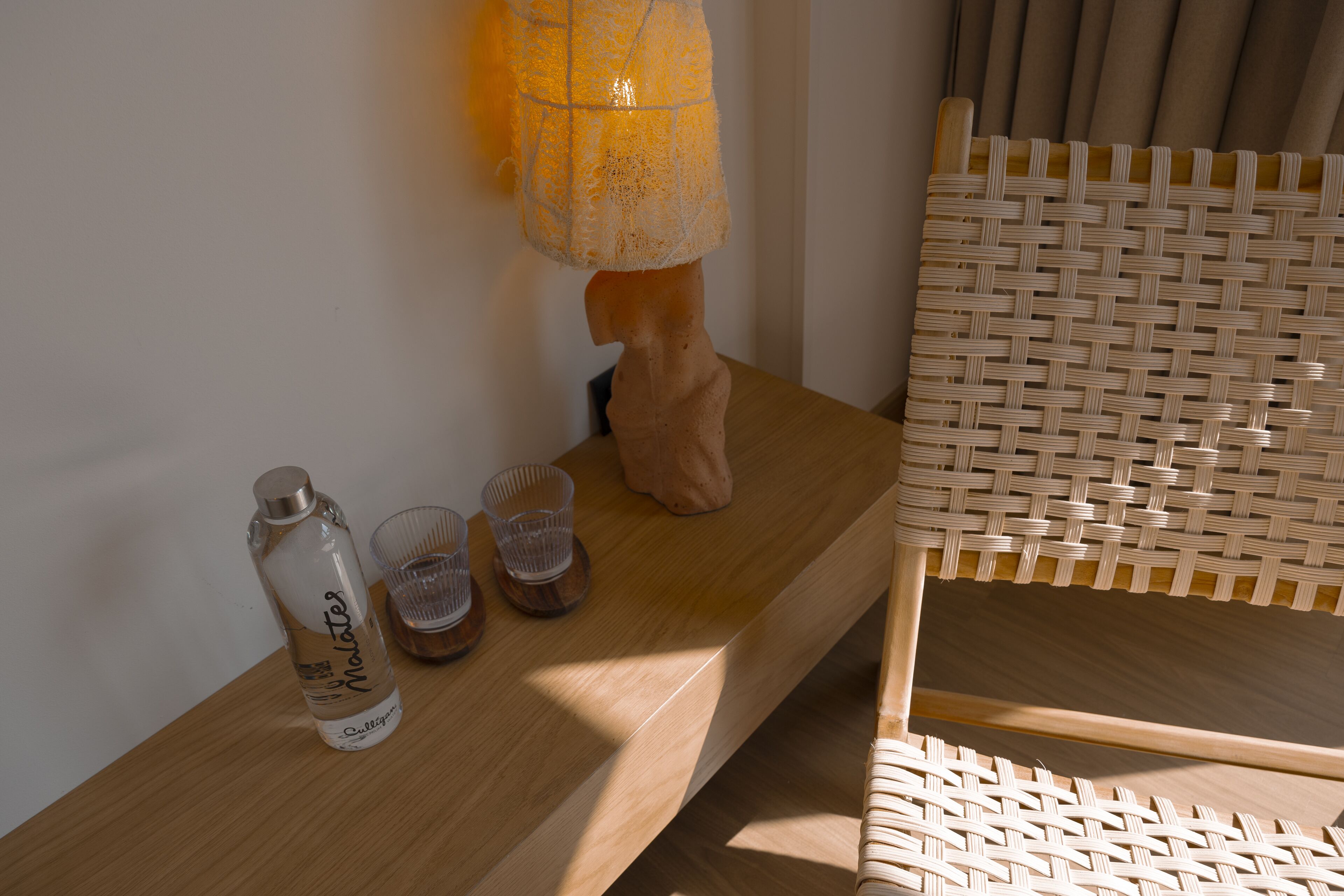 A wooden table with a water bottle, two glasses, and a decorative item.