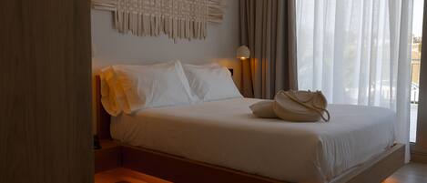 A modern bedroom with a wooden platform bed, white linens, and a woven wall art piece.