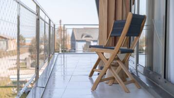 Een balkon met een houten stoel en een metalen hek.
