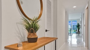 Un pasillo con una consola de madera, un cesto tejido para plantas y un letrero de prohibido fumar.