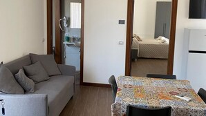 A compact living space with a sofa, dining table, and kitchenette. - La Torre - Deluxe Apartment 1 (Santo Stefano di Camastra)