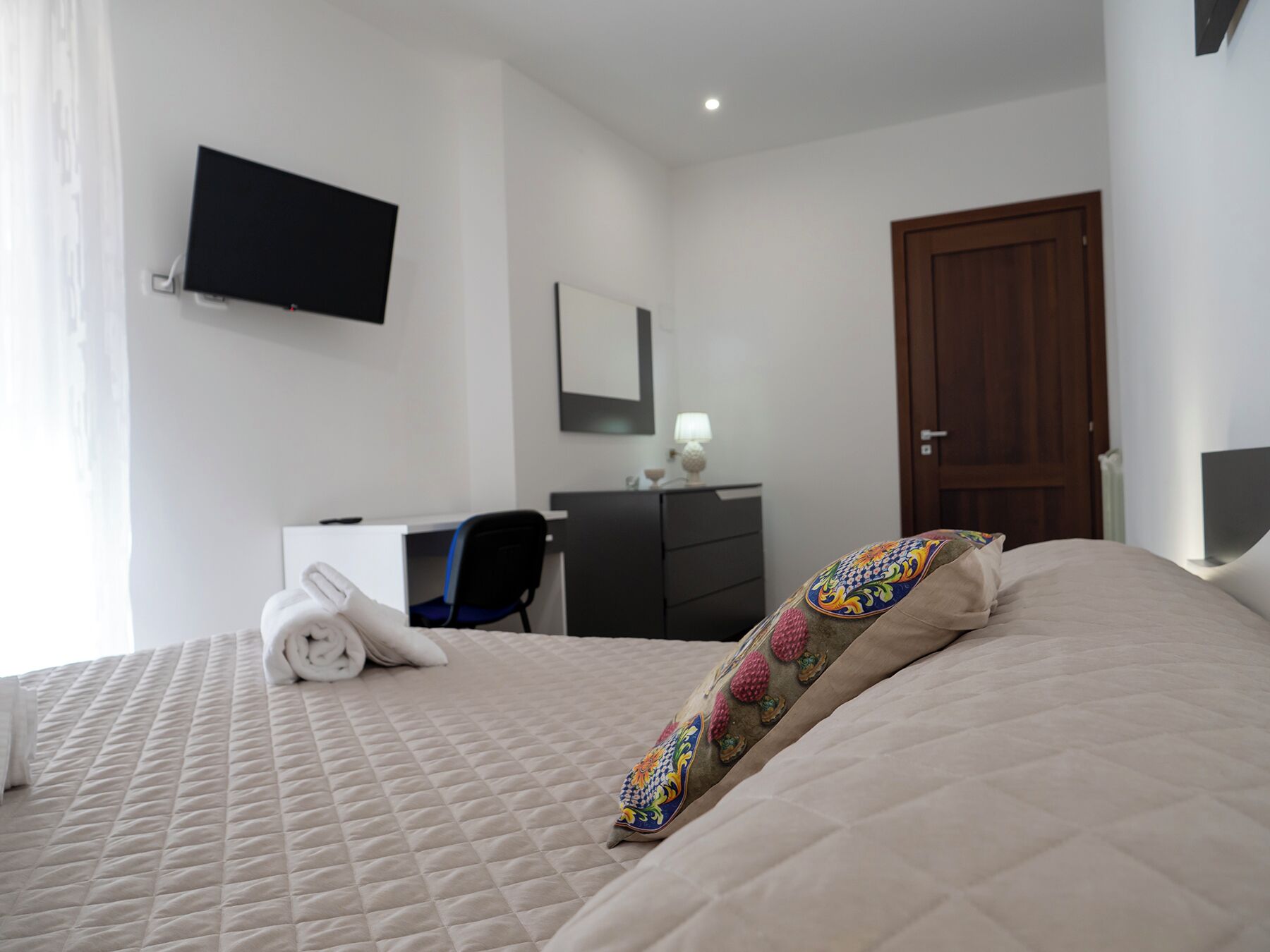 Una habitación de hotel con una cama, un escritorio, una silla, un televisor y un armario.