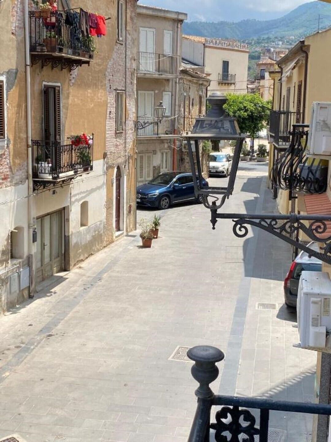 Una calle estrecha flanqueada por edificios, con un coche aparcado y un farol.