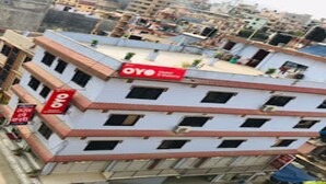 Un immeuble à plusieurs étages, doté d’une façade rouge et blanche, sur laquelle on peut voir une grande enseigne « OYO » sur le toit.