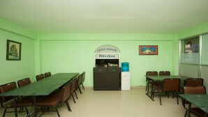 Une salle de conférence équipée d’une longue table et de chaises, d’un réfrigérateur et d’un distributeur d’eau.