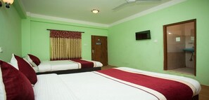 Une chambre d’hôtel avec deux lits, un ventilateur de plafond, une télévision et une porte donnant sur une salle de bain.