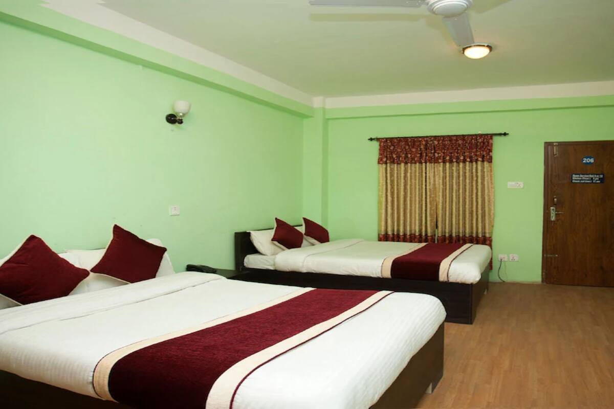Habitación de hotel con dos camas, un ventilador de techo, un televisor y una puerta con un cartel.