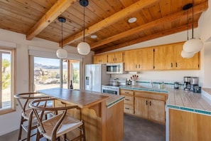 Une cuisine avec des meubles en bois, un îlot central et des luminaires suspendus.