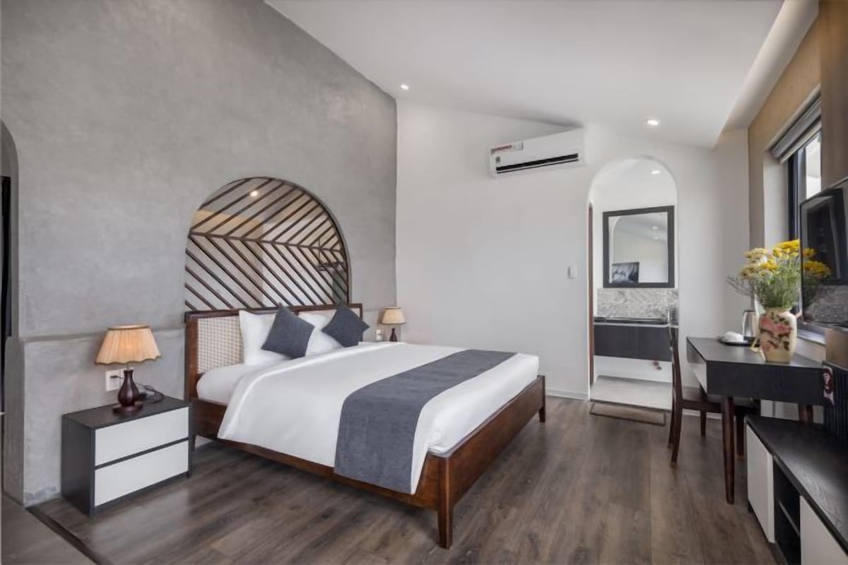 A modern bedroom with a bed, bedside tables, a desk, and a mirror.