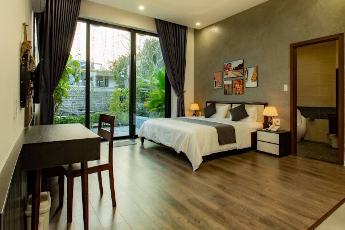 A modern bedroom with a bed, bedside tables, a desk, and a chair.