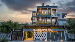 Un immeuble moderne à plusieurs étages, sur lequel on peut lire l’inscription : « Charm Champion Villa ».