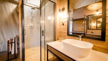 A modern bathroom with a glass-enclosed shower, a large white sink, and a wooden vanity.