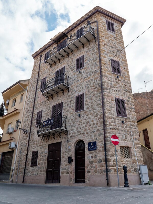 A stone building with multiple balconies, a sign reading "TORRE," and a no entry sign.