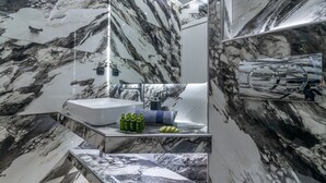 Een moderne badkamer met een marmeren wastafel, een grote spiegel en een ingebouwd toilet.