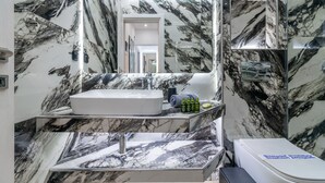 Een moderne badkamer met een groot marmeren wastafel, een spiegel en een douchehoek.