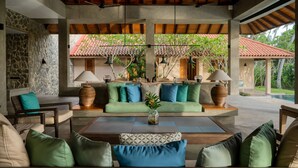 A covered outdoor seating area with a stone wall, a green sofa, and a wooden coffee table. - Kirana - A Santani Villa (Bentota)