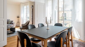 A dining area with a table and chairs, a candelabra, and a view of the outside balcony.