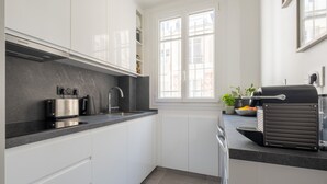 A modern kitchen with white cabinets, a built-in toaster, a sink, and a window with a view of the city.