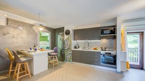 A modern kitchen with a central island, built-in appliances, and a view to the outside. - Casa Gio Near the Waterfall Varone (Riva del Garda)