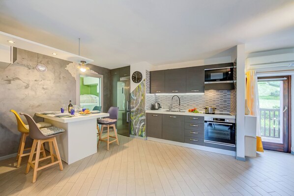 A modern kitchen with a central island, built-in appliances, and a view to the outside.