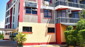 A multi-story building with balconies, air conditioning units, and a sign indicating it is a hotel. - DIVINE HOMES RESORT KISUMU (Kisumu)