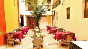 A corridor with tables and chairs, each with a red tablecloth and a small decorative item on the table. - DIVINE HOMES RESORT KISUMU (Kisumu)
