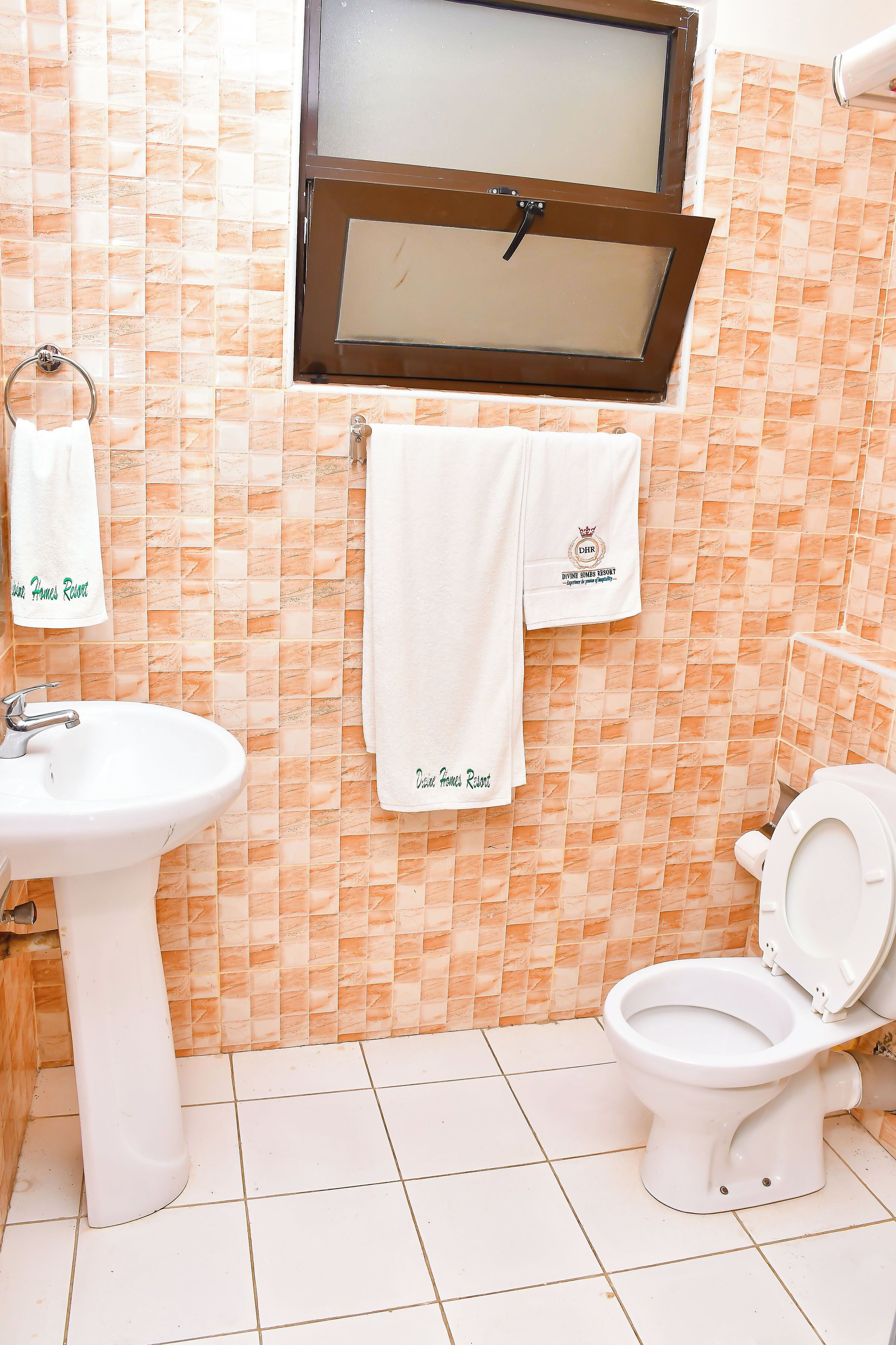 A bathroom with a sink, toilet, and a window with a brown frame.