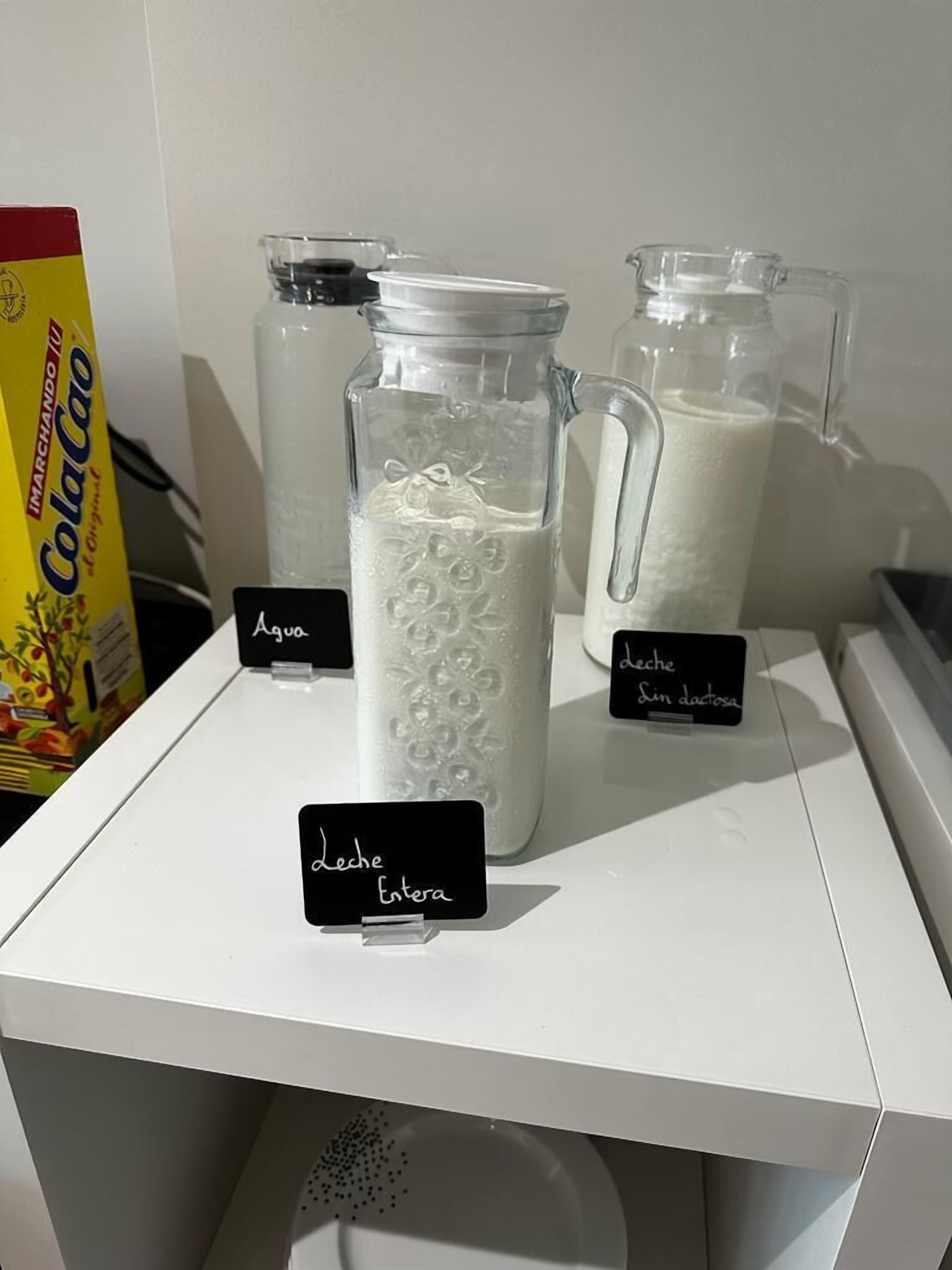 A shelf with three glass containers labeled with different types of milk.