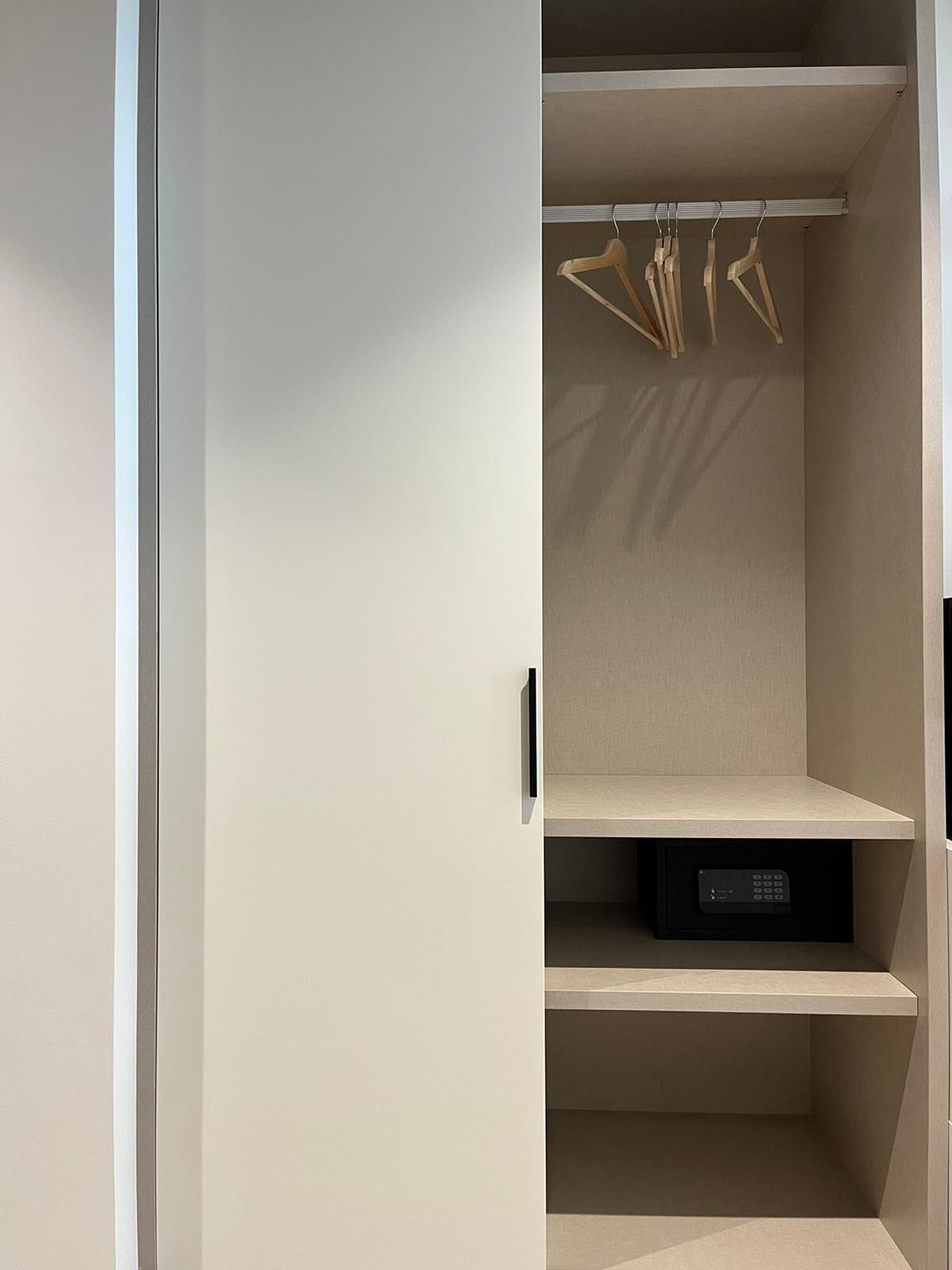 A closet with multiple shelves and hanging space, a control panel, and a door with a handle.