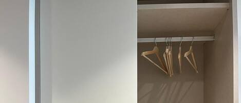 A closet with multiple shelves and hanging space, a control panel, and a door with a handle.