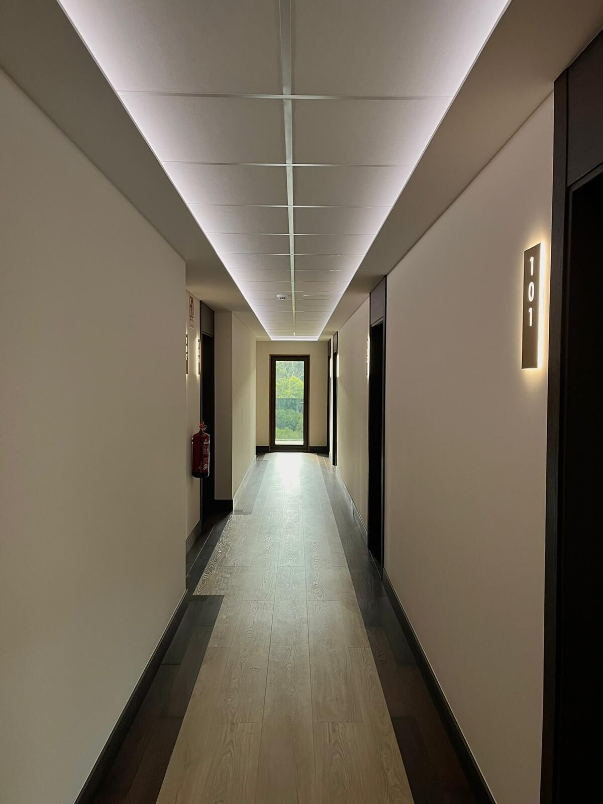A long, narrow hallway with a tiled floor and a ceiling with recessed lighting.