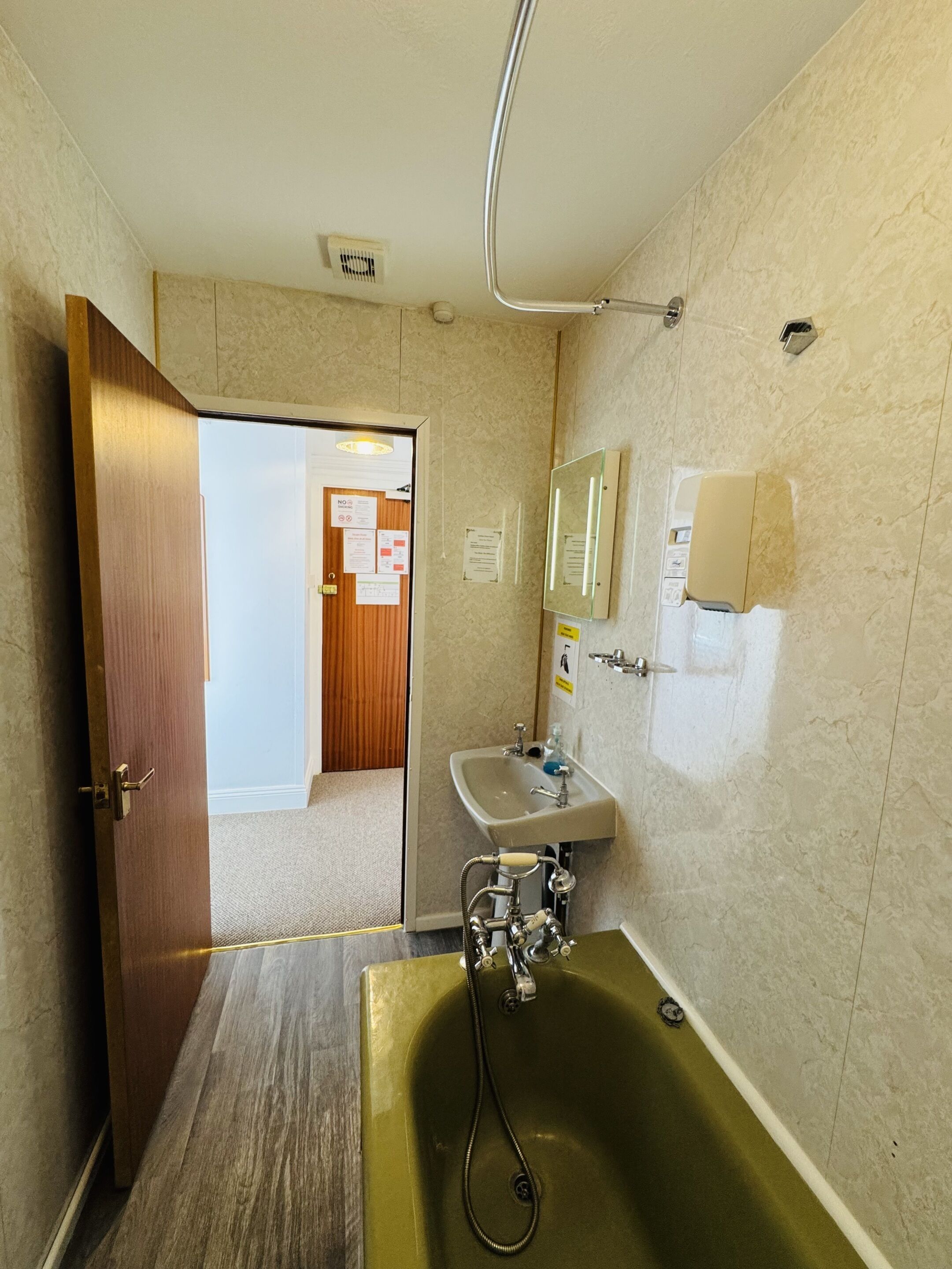 Ein Badezimmer mit Holztür, Waschbecken, Spiegel und Badewanne.