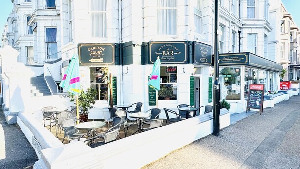 A Carlton Court Hotel with outdoor seating and a bar.