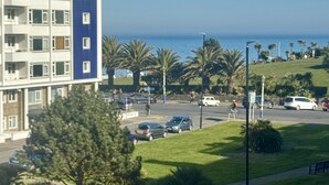 A multi-story building with a blue and white facade, located near a road with parked cars and palm trees.