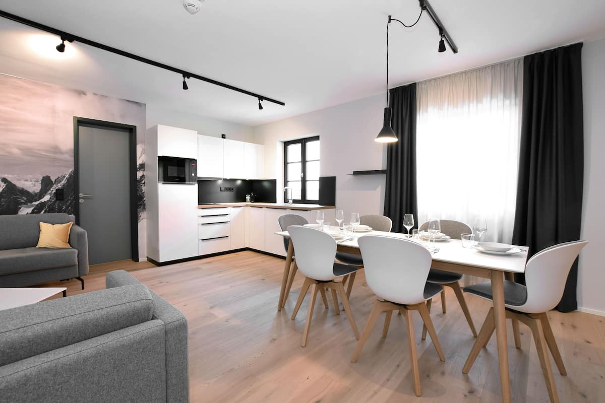 Una cocina moderna con armarios blancos, un microondas y un comedor con una mesa preparada para cuatro.