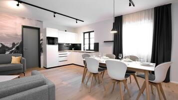 A modern kitchen with white cabinets, a microwave, and a dining area with a table set for four.