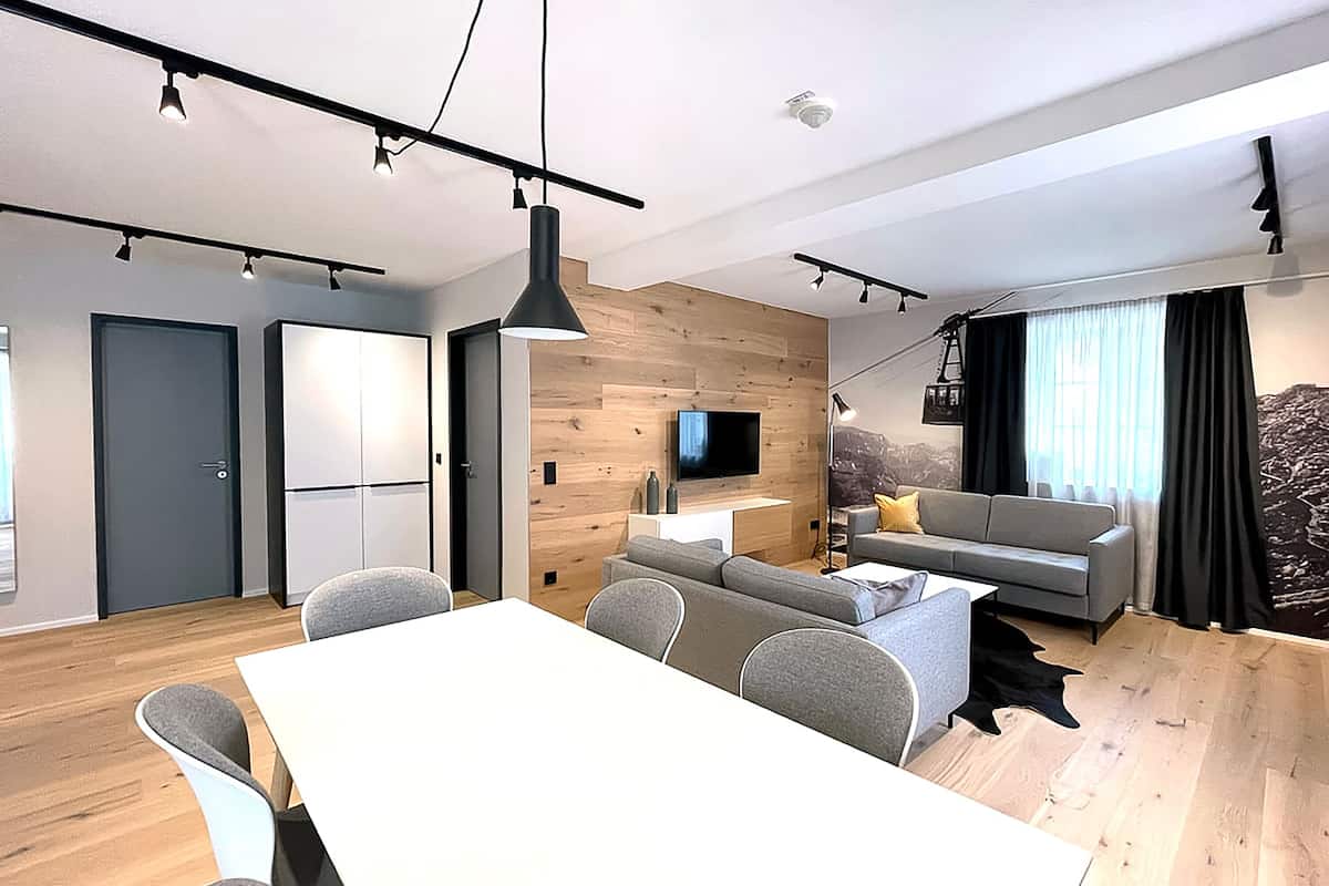Una sala de estar moderna con sofá, televisión y comedor.