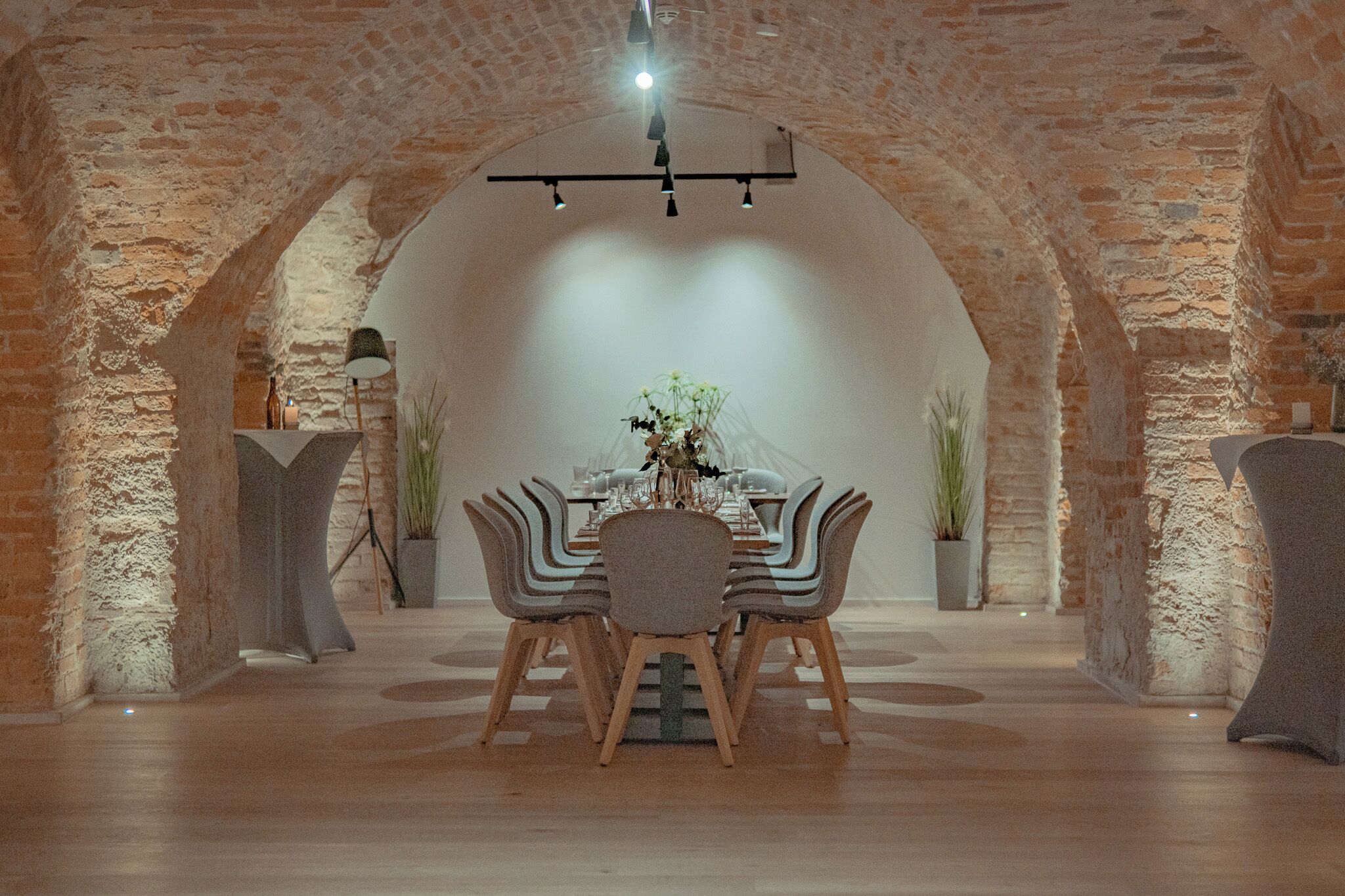 A dining area with a brick archway, a table set with chairs, and a hanging light fixture.