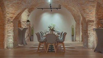 A dining area with a brick archway, a table set with chairs, and a hanging light fixture.