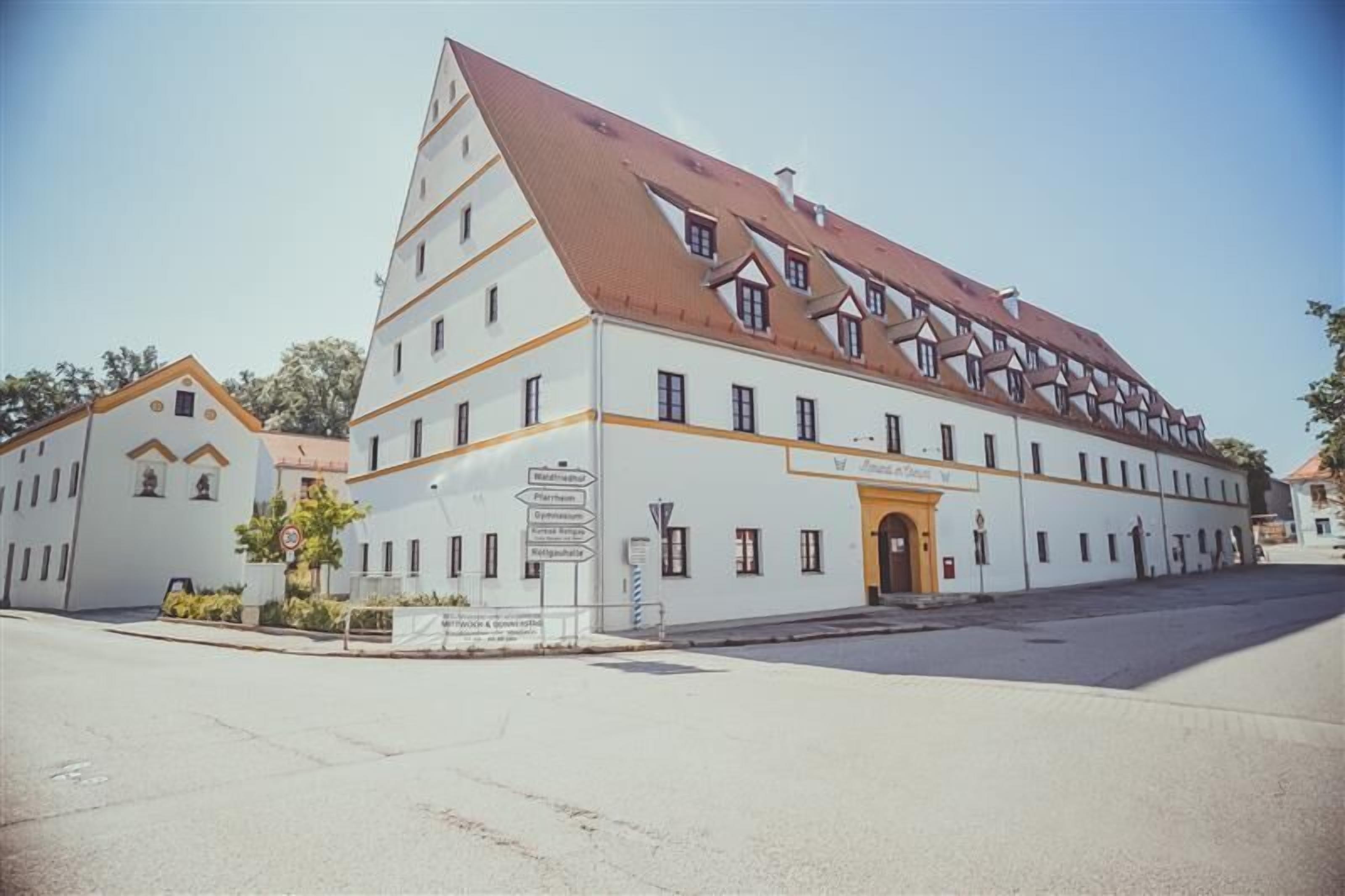A large, white building with a brown roof and multiple windows.
