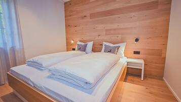 A modern bedroom with a wooden headboard, a neatly made bed with white linens, and a small bedside table.