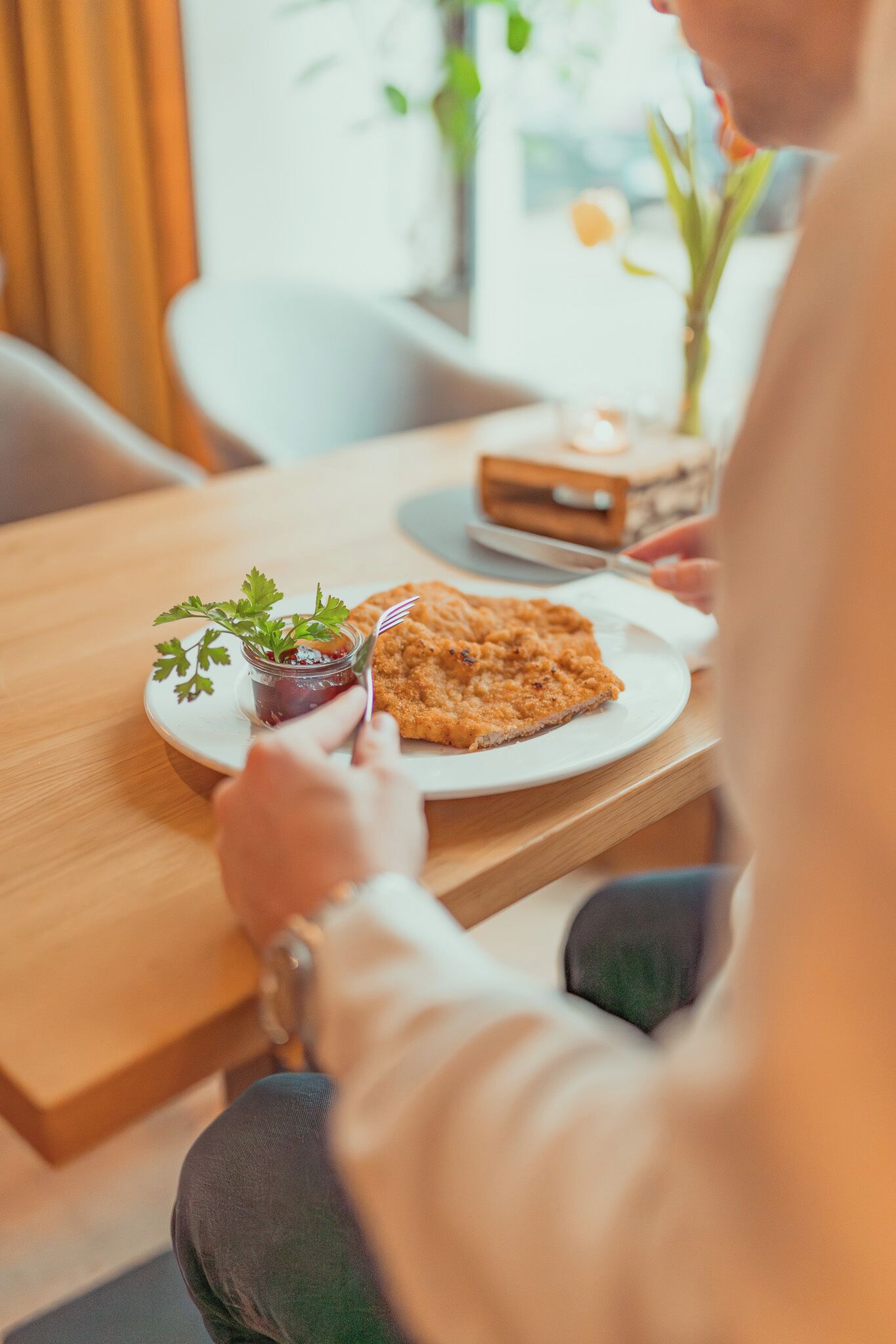 A dining table with a plate of food, a jar of sauce, and a small plant.