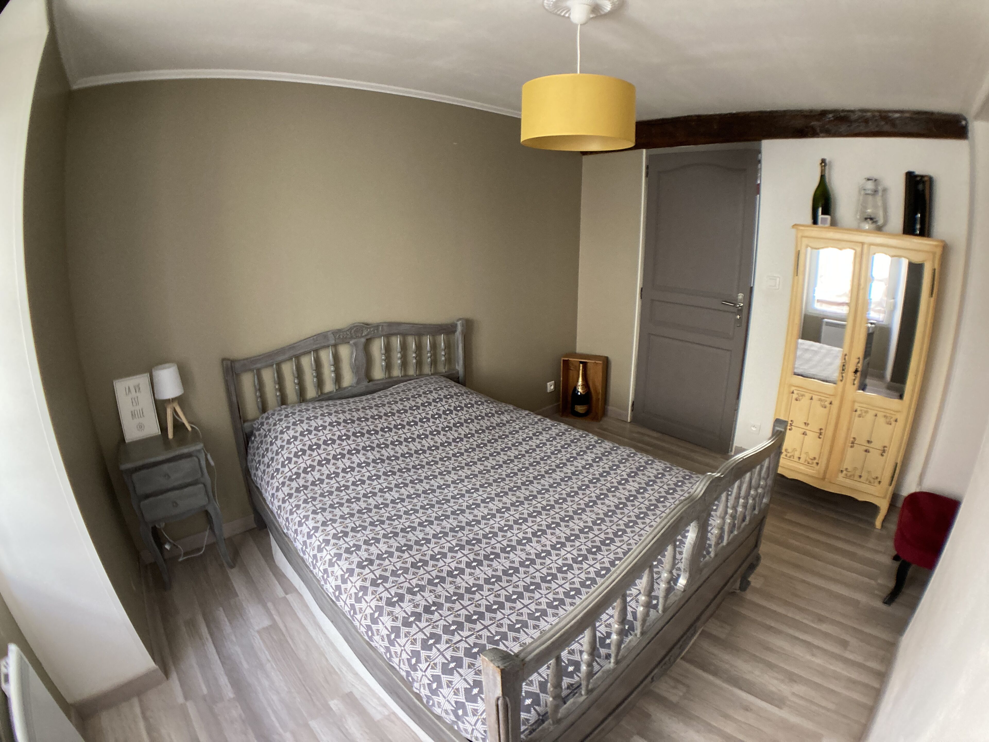 Un dormitorio con cama, mesita de noche, armario e iluminación colgante.