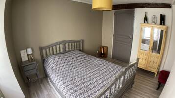 Un dormitorio con cama, mesita de noche, armario e iluminación colgante.