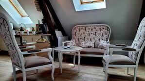 A cozy loft-style room with a high ceiling, a skylight, a sofa, two armchairs, a small round table, and a wooden floor. - Character house from 1894 in the heart of the Champagne vineyards, near Epernay (Avize)