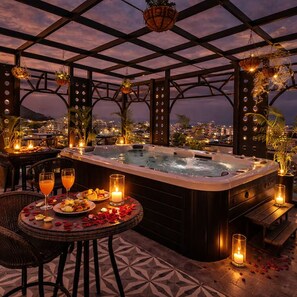 A rooftop terrace with a hot tub, dining area, and city views at dusk. - My Downtown - Prime A Premium Boutique Hotel Udaipur (Udaipur)