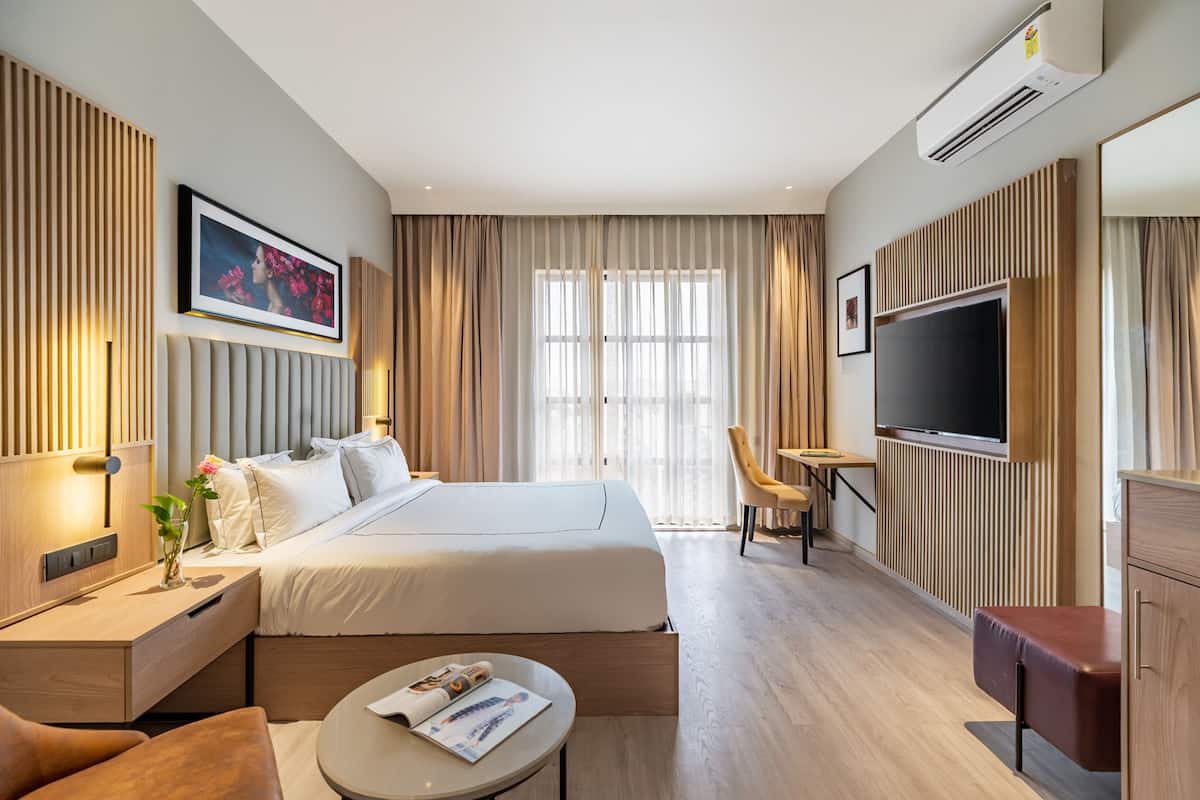 Una habitación de hotel moderna con una cama grande, un televisor, un escritorio y una silla.