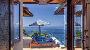 A balcony with blue lounge chairs and striped umbrellas overlooking the ocean. - Villa Varya (Kamala)